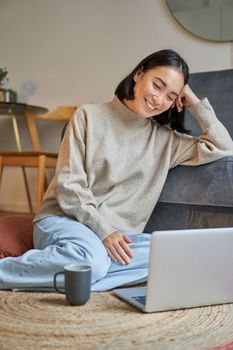 Vertical shot of beautiful asian woman, student sitting at home and studying remotely, elearning with laptop.