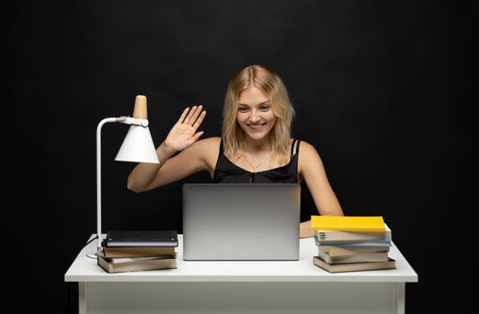 Positive cheerful woman, business woman, entrepreneur, freelancer at a table in office have video call with a business partners