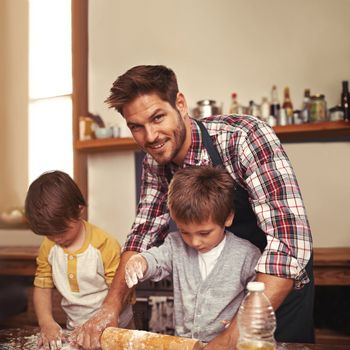 They love baking. two young brothers baking with their father in the kitchen