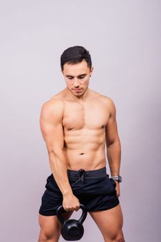 Sporty man working out with kettlebell. Photo of man on dark background. Strength and motivation