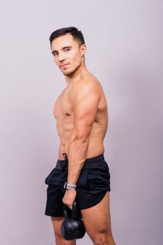 Sporty man working out with kettlebell. Photo of man on dark background. Strength and motivation