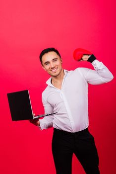 Image of young cheerful businessman holding and using laptop isolated over red background