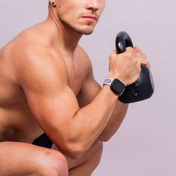 Handsome muscular man holding a kettle bell with copy space. Hispanic male athlete