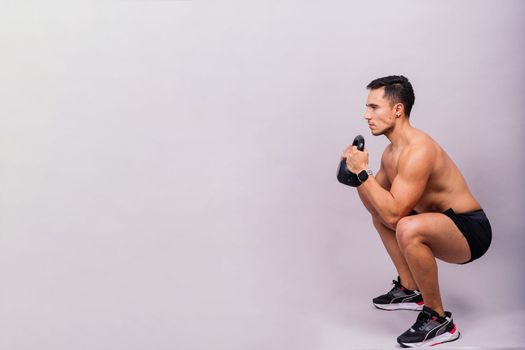 Sporty man working out with kettlebell. Photo of man on dark background. Strength and motivation