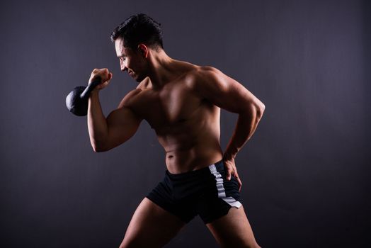 Sporty man working out with kettlebell. Photo of man on dark background. Strength and motivation