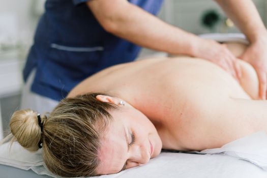 Young fat woman getting massage treatment in a day spa cabinet.