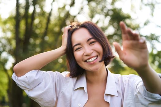 People and emotions concept. Happy asian woman laughing and smiling, posing on summer day in park. Copy space