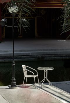 Bangkok, Thailand - 26 Jan, 2023 - The white metal chair and the table beside street lamp pole, Relaxing corner in the sunny day with good atmosphere, Space for text, Selective focus.
