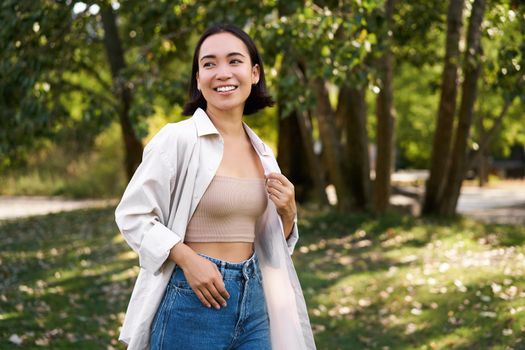 Stylish asian girl walks in park, laughs and enjoys summer weather. People and lifestyle concept.