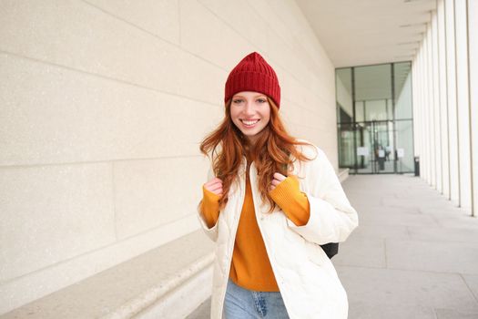 Young tourist, happy girl walking around european city with backpack, student goes to university, goes somewhere in town. Copy space