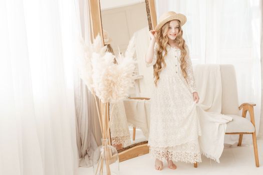 A beautiful teenage girl with long hair measures a straw hat in front of a mirror. Self-admiration of a blonde. selective focus