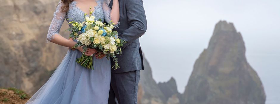 a couple standing in an embrace holding a beautiful bouquet of flowers, a girl dressed in a blue long dress, a man dressed in a suit. wedding concept.