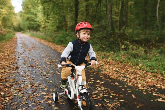 Boy in helmet learns riding a four-wheeled bicycle