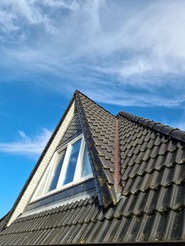 Open roof window in velux style with black roof tiles