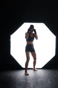 Young woman athletic female MMA fighter is training. Concept of sport, action, healthy lifestyle.