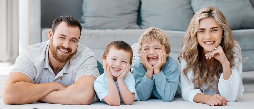 Portrait of smiling caucasian family of four lying and relaxing on the floor at home. Carefree loving parents bonding with cute little sons. Playful young boys spending quality time with mom and dad.