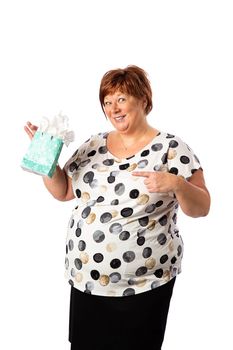 Isolated portrait of a fifty year old overweight red hair woman pointing at gift bag