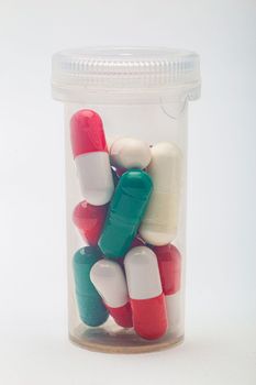 Bottle containing multi-colored pill inside a transparent bottle