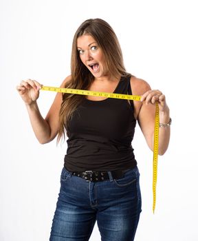 Isolated portrait of a forty year old woman wearing a tank top, holding a yellow mesuring tape, with a surprise expression