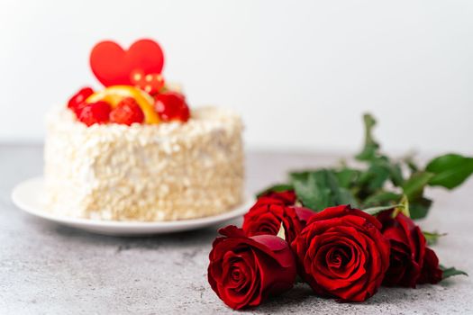 Roses flowers and Valentine's Day cake with heart shape and fruits, strawberries. Birthday Cake for celebration. Valentine's Day and love concept. Present with love.