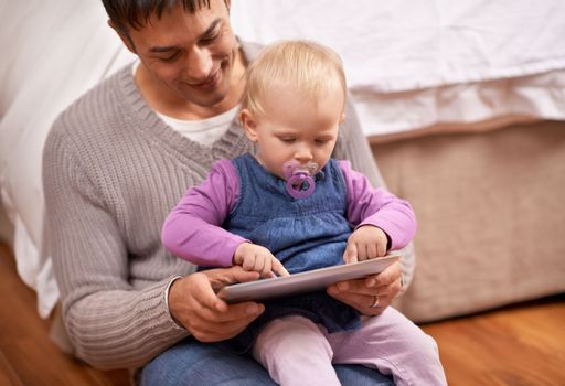 Showing dad how its done. A young father showing his baby girl something on a digital tablet