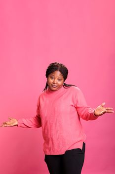 Smiling optimistic person with surprised reaction having fun in studio, feeling cheerful and relaxed in front of camera. Female model having positive energy and showing playful amusing symbol.