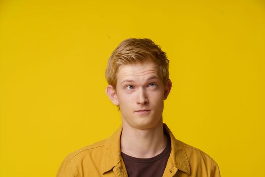 A Frivolous Teenage Student Is Fooling Around in A Denim Jacket on A Yellow Background. Making Faces. High quality photo