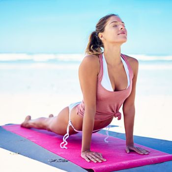 Yoga slows you down and puts you in the now. a young woman doing yoga at the beach