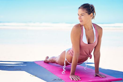 Yoga improves your overall quality of life. a young woman doing yoga at the beach