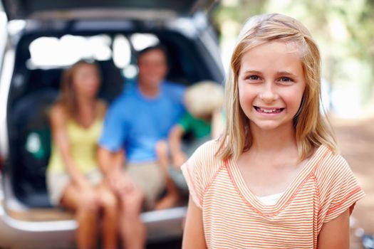 Cute young girl smiling. Portrait of cute young girl smiling with family sitting in the back of a car