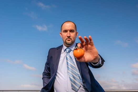Male persimmon park. Hipster millennial man in a tie and jacket bites off a persimmon while sitting on a park bench in slow motion Young business people eat golden persimmons at lunchtime