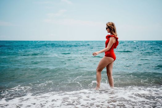 Young happy woman walks carefree on the seaside. Happy lady in red bikini. Portrait beautiful young woman relax smile around beach sea ocean in holiday vacation travel trip.