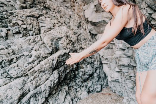 A girl climbs a rock. The athlete trains in nature. Woman overcomes difficult climbing route. Extreme hobby. Tourist woman rock climber hiking on mountains rocks over beautiful sea coast