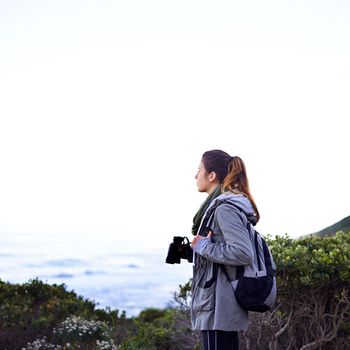 Appreciating the beauty of nature. a young woman using binoculars while out hiking