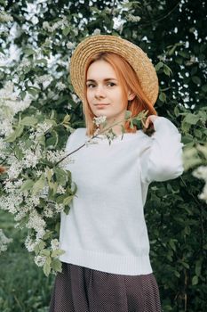 Portrait of a woman in a straw hat in a cherry blossom. Free outdoor recreation, spring blooming garden
