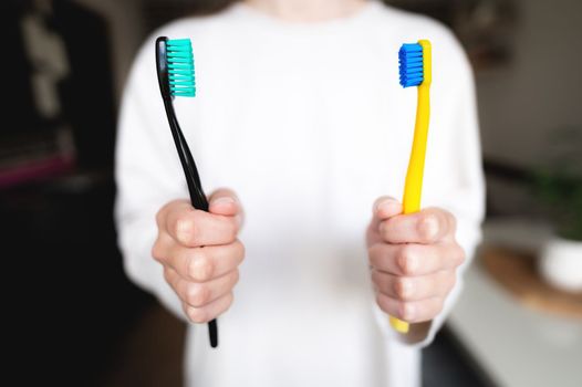 Woman's hand holds two toothbrushes. Dental direction, the subject of the morning hygiene of a married couple.