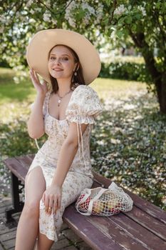 An attractive long-haired woman walks in the spring in the park of blooming apple trees. Spring portrait of a woman