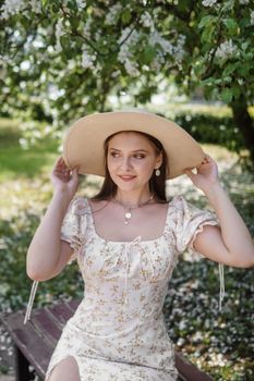 An attractive long-haired woman walks in the spring in the park of blooming apple trees. Spring portrait of a woman