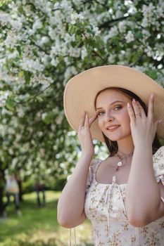 An attractive long-haired woman walks in the spring in the park of blooming apple trees. Spring portrait of a woman