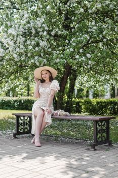 An attractive long-haired woman walks in the spring in the park of blooming apple trees. Spring portrait of a woman