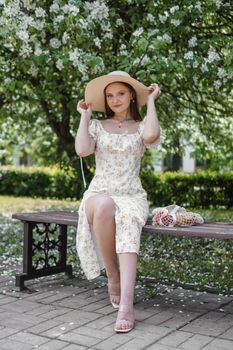 An attractive long-haired woman walks in the spring in the park of blooming apple trees. Spring portrait of a woman