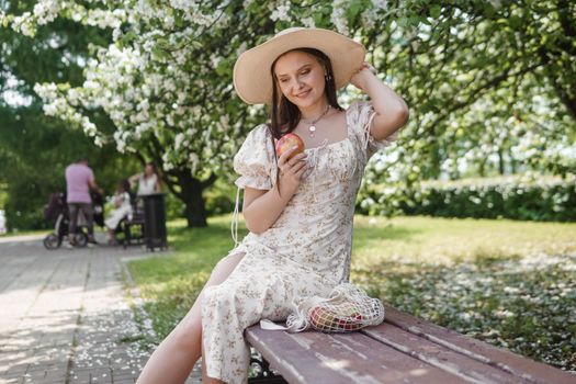 An attractive long-haired woman walks in the spring in the park of blooming apple trees. Spring portrait of a woman