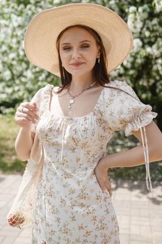 An attractive long-haired woman walks in the spring in the park of blooming apple trees. Spring portrait of a woman