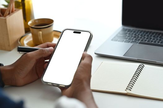 Close up view of man sitting on bright office and using smart phone.Empty screen for your advertise design.