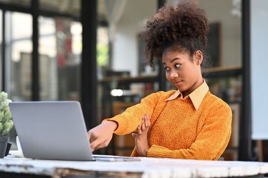 Playful African American woman freelancer working remote with laptop computer at outdoor cafe.