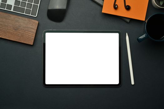 Flat lay digital tablet with empty screen, stylus pen, notebook and coffee cup on black leather.