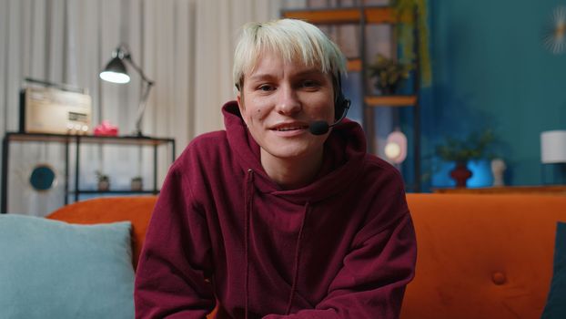 POV of woman with short hair at home wearing headset, freelance worker call center or support service operator helpline having talk with client or colleague communication support. Girl in evening room