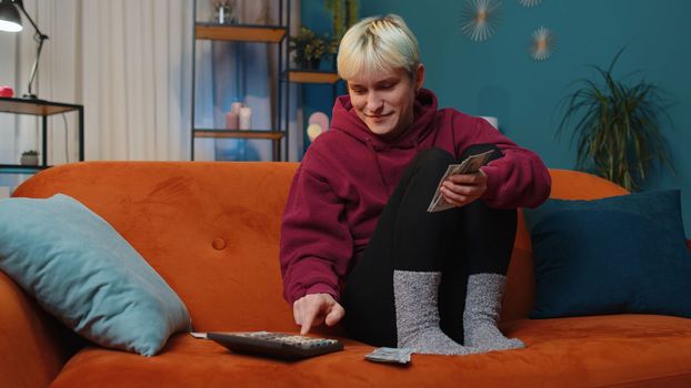 Planning budget. Rich woman with short hair counting money cash use calculator and calculate domestic bills at home. Girl satisfied of income earnings, win, saves money for planned vacation, gifts