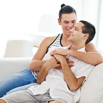 Lets just stay here all day. a young gay couple relaxing on a sofa at home