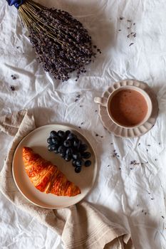 breakfast of croissant, grapes and hot chocolate, morning scene on the bed, top view